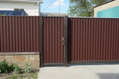 bir kapalı kahverengi metal kapı ve caddedeki çitin bir kısmı 