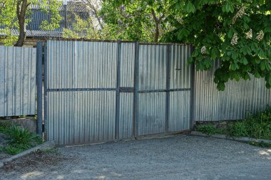 Büyük, gri bir metal kapı ve çitin bir kısmı.