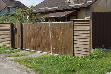 Kapalı kahverengi kırsal ahşap kapı ve yeşil çimlerin üzerindeki kalaslardan yapılmış çitler.