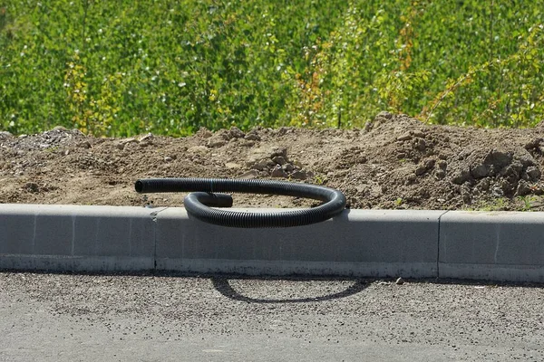 Egy Fekete Műanyag Tömlő Fekszik Egy Szürke Beton Járdán Földön — Stock Fotó