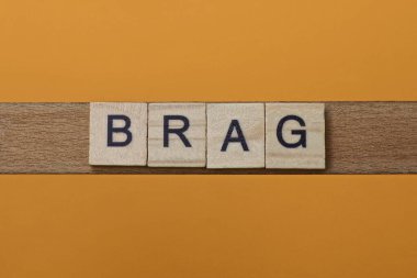 Kahverengi arka planda ahşap kare harflerden yapılmış gri kelime.