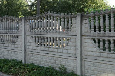 Kırsal bir sokakta yeşil çimlerde büyük, beyaz beton bir duvarın parçası.