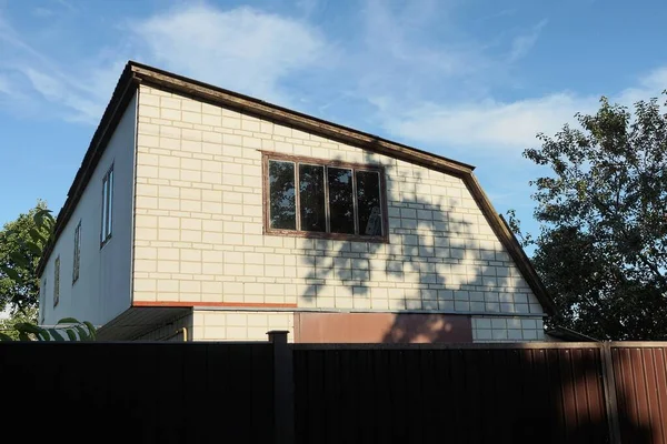 蓝色天空下的褐色篱笆后面的一座私人住宅的白色砖墙阁楼 — 图库照片
