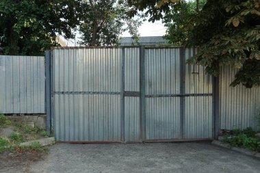 Bir gri kapalı metal kapı ve sokaktaki çitin bir kısmı