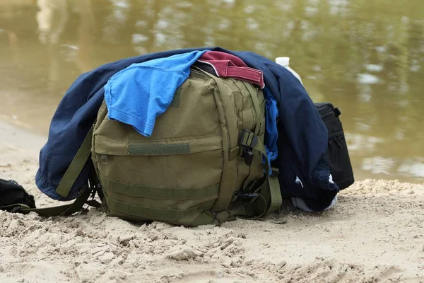 Uma Mochila Verde Exército Monte Roupas Coloridas Fica Areia Praia — Fotografia de Stock