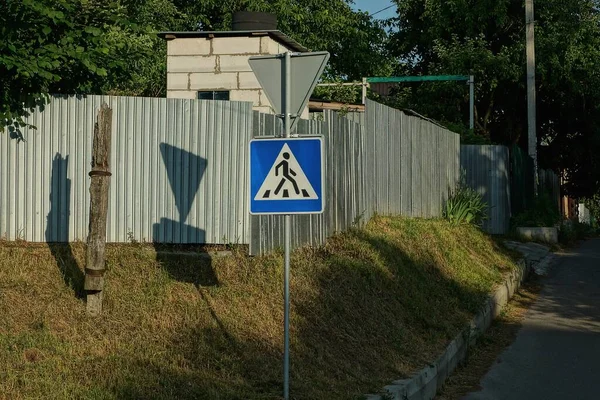 灰色の金属製の柵の近くの通りを横断する一本の正方形の道路標識 — ストック写真