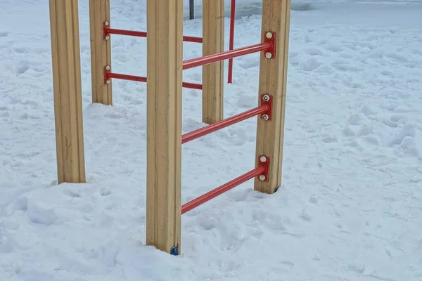 part of brown red stairs in white snow on a playground on a winter street