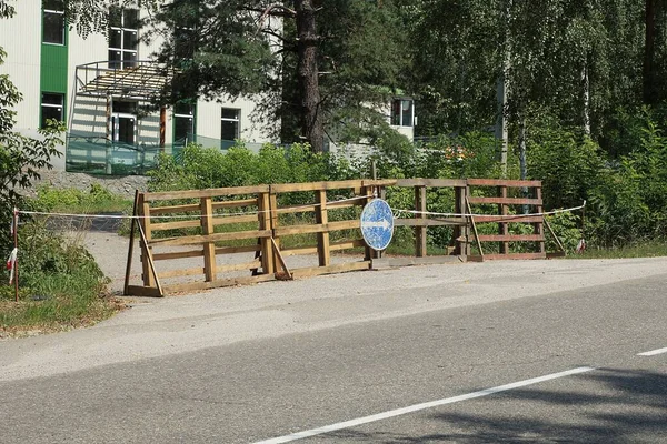 重建道路的一部分被木板护栏和一个蓝色路标挡住 街道上的沥青路面上有一个白色箭头 — 图库照片