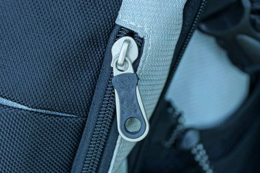 Büyük bir sırt çantasının kumaşında bir beyaz siyah metal fermuar.