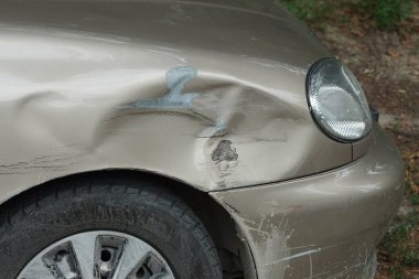 Yıpranmış gri bir arabanın parçası. Kanat lambası ve tamponu yıpranmış.