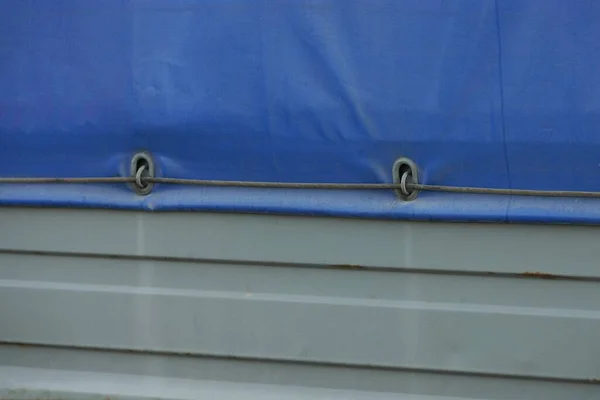 一辆装有钢丝绳的汽车拖车铁灰色侧面上的一块蓝色防水油布 — 图库照片