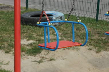 boş bir renk salıncak koltuğu açık havada gri demir zincirlerde asılı yeşil çimen arka planda kahverengi zemin karşı