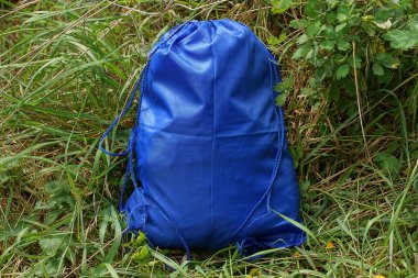 Sentetik kumaştan yapılmış bir çanta doğada yeşil çimlerde duruyor.