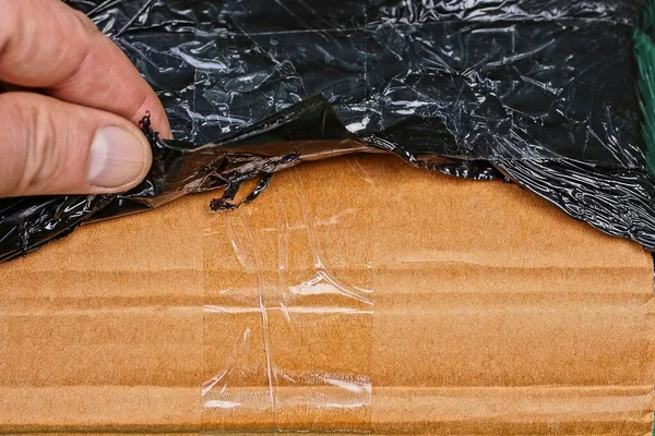 Dedos Rasgando Embalagem Celofane Preto Caixa Papelão Marrom Parcela — Fotografia de Stock