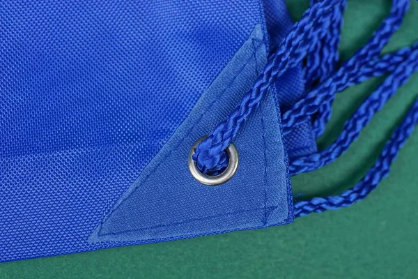 绿色桌子上背包织物上灰色金属环中的蓝绳花边 — 图库照片