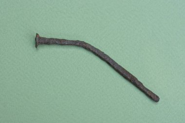 Yeşil bir masada eski kahverengi eğri bir çivi yatıyor.