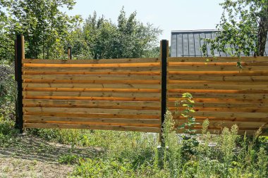 Çitin kahverengi duvarının bir kısmı yeşil çimenlerdeki tahtalardan yapılmıştı.