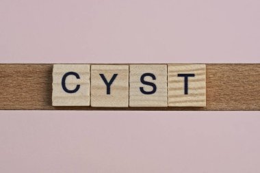 Kist kelimesini gri ahşap küçük harflerle yaz. Üzerinde siyah yazı tipi olan pembe masa.