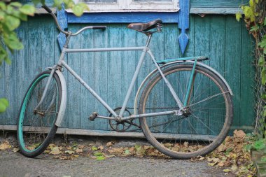 Kırsal kesimdeki bir evin ahşap yeşil duvarında arka planda bir eski gri bisiklet.