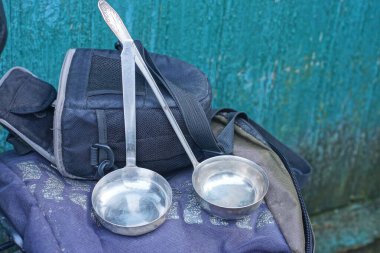 İki gri eski metal kepçe ve kaşıklar yeşil duvarın yanındaki masada yatıyor.