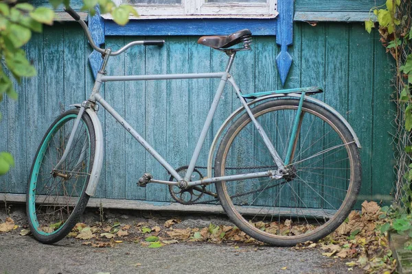 Kırsal kesimdeki bir evin ahşap yeşil duvarında arka planda bir eski gri bisiklet.