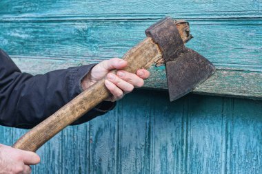 Güz sokağında yeşil duvara yaslanmış büyük gri kahverengi baltayı tutan siyah elbiseli bir el.