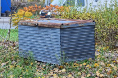 Büyük, kapalı bir metal kutu caddedeki yeşil çimlerin üzerinde duruyor.