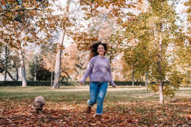 Harika bir sonbahar gününde, parkta köpeğiyle eğlenen güzel bir kadın. Yaşam tarzı ve açık hava hayvanları