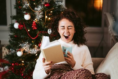 Aralık ayında soğuk bir günde bir fincan çayla kitap okurken esneyen güzel bir kadın. O bir Noel ağacının yanında oturuyor ve bir battaniyeyle kaplı. Noel tatili kavramı