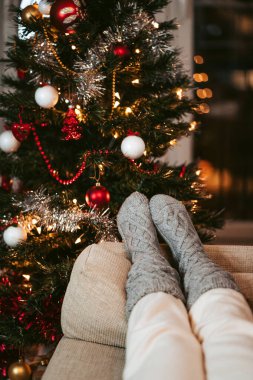 Bir Noel ağacının yanındaki koltukta iki ayak dinleniyor. Noel arkaplanı kavramı