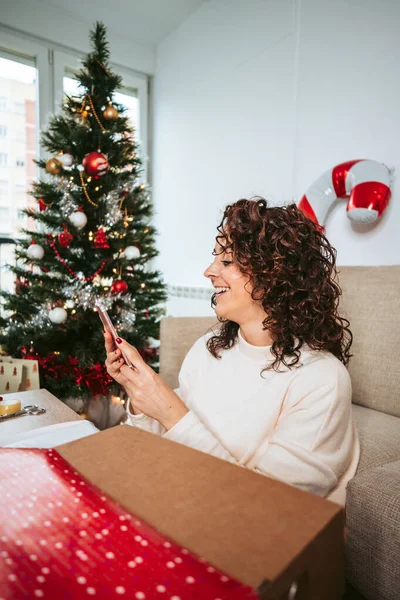 Una Hermosa Mujer Preparando Regalos Navidad Mientras Mira Algo Teléfono — Foto de Stock