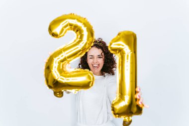 Yeni yıl arifesinde balonları kameraya gösterirken elinde 21 numaralı balonla iki büyük altın balon tutan esmer bir kadın. O bir pijama giyiyor. Yeni yıl partisi ev kavramında