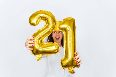 Kapatın. Seçici odaklanma. Kameraya yirmi bir numaralı balonu gösteren bir kadın. Pijama ve silindir şapka giyiyor. Yeni Yıl Arifesi ev kavramında