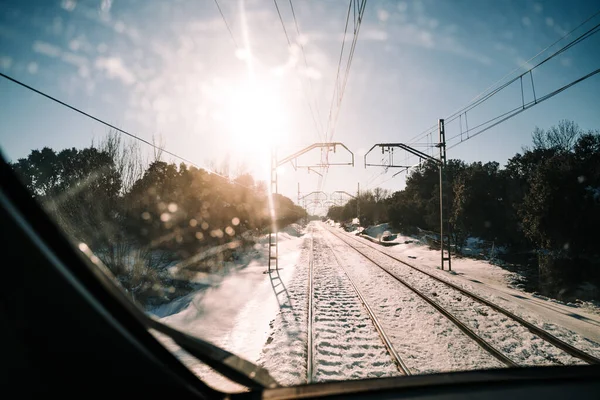 View of the railway of a train with snow around them in a beautiful day with the sun in the sky. Traveling by train in a snowy and sunny day. Concept of landscape of snowy railway.