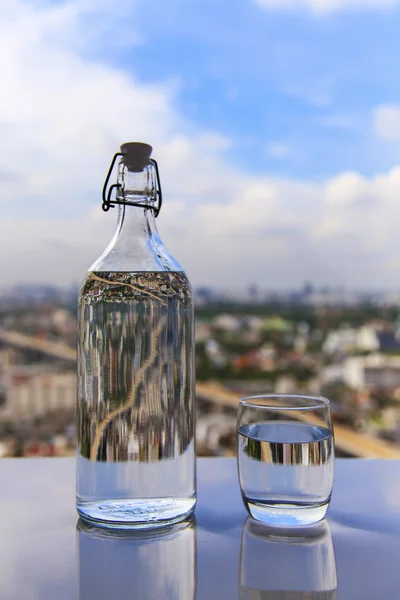 Sklenici vody s lahví o stůl — Stock fotografie