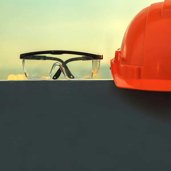 Casca de siguranță și ochelari de protecție cu șantier de construcții în fundal — Fotografie, imagine de stoc