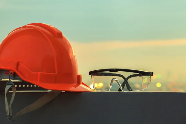 Safety helmet and goggles with construction site in the background — Stock Photo, Image