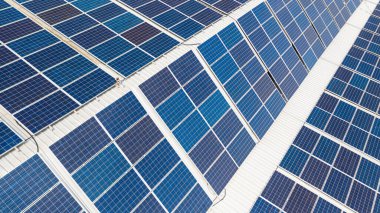 Çatıdaki güneş pillerinin hava görüntüsü, büyük bir endüstriyel binanın çatısına kurulmuş güneş panelleri veya insansız hava araçlarıyla çekilmiş bir depo.