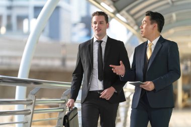 İş adamları modern ofisin önünde yürür ve birbirleriyle konuşurlar. 