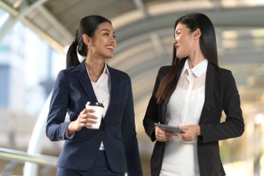 İş adamları modern ofisin önünde yürür ve birbirleriyle konuşurlar. 