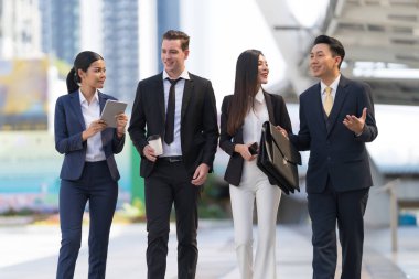 İş adamları modern ofis, liderlik konsepti ve iş başarısı önünde yürür ve birbirleriyle konuşurlar.