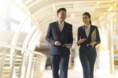 İş adamları modern ofisin önünde yürür ve birbirleriyle konuşurlar. 