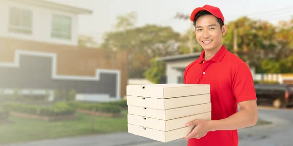 Delivery man employee in red t-shirt uniform holding empty cardboard box with Blur building of Background