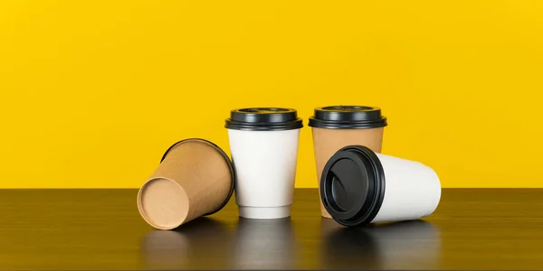 Blank paper coffee cup set on yellow background
