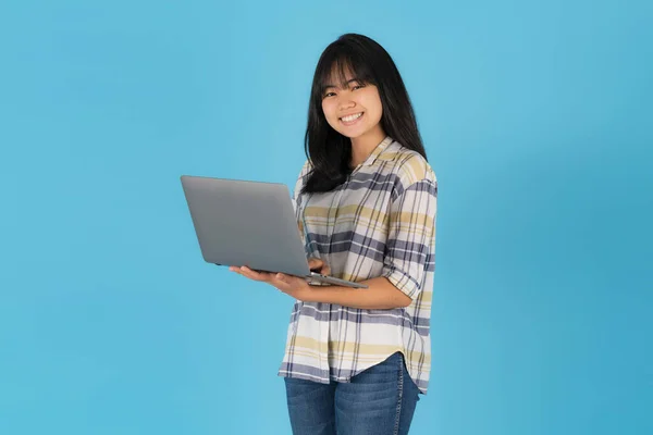 快乐的亚洲女孩 站在蓝色背景的笔记本电脑旁 — 图库照片