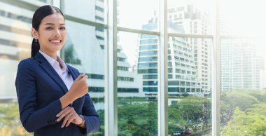 Modern ofis binalarında dururken gülümseyen iş kadınının portresi