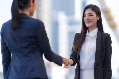 Kapanış, modern ofisin arka planında iki iş kadınının el sıkışması, ortaklık konsepti, anlaşma imzalamak için el sıkışması.