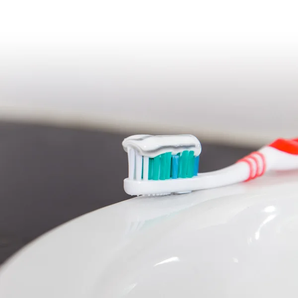 Zahnbürste mit Zahnpasta im Waschbecken — Stockfoto
