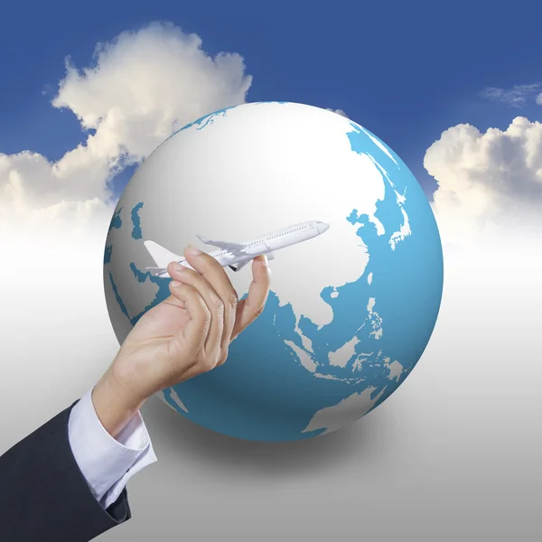 Airplane in hand with world globe icon on blue sky — Stock Photo, Image