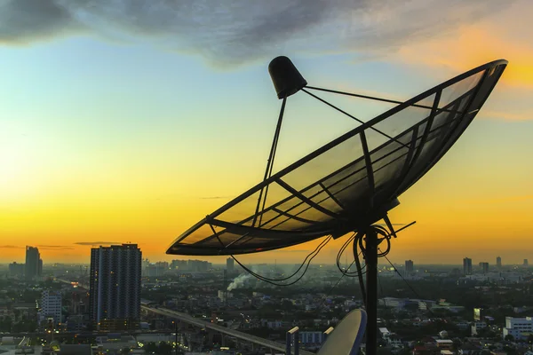 Uydu çanağı gökyüzünde alacakaranlık şehir — Stok fotoğraf